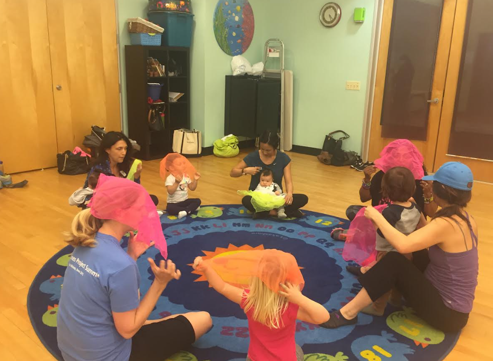 Parents and children playing together with colorful scarves in class circle